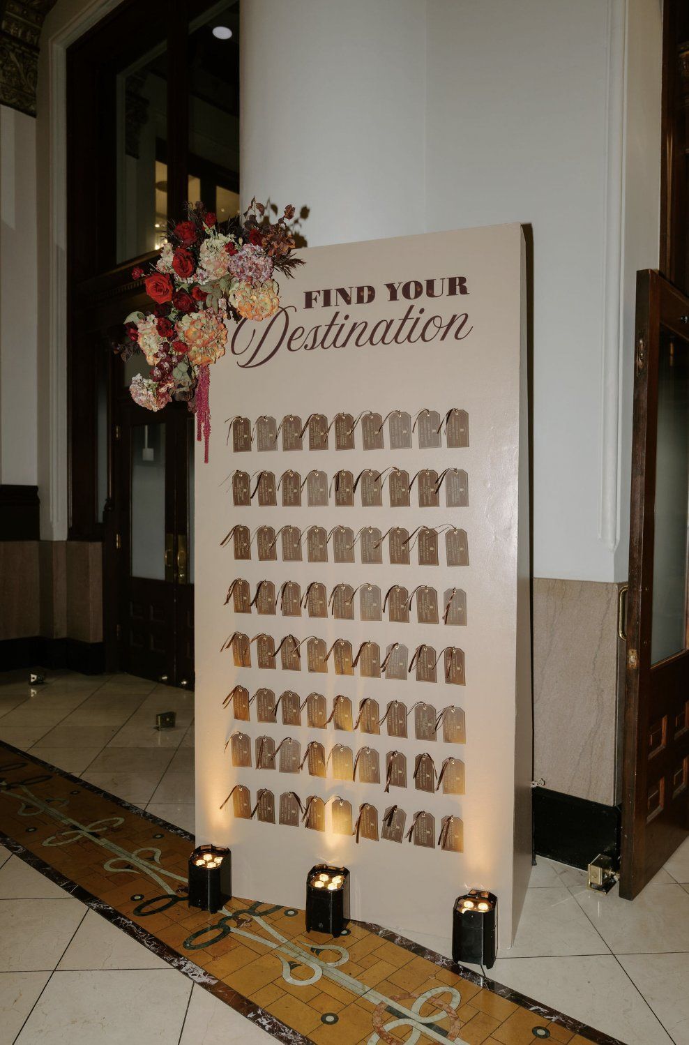 Wedding seating chart: beige board with tags, floral arrangement, candles by Luxury Wedding Planners in Nashville, TN