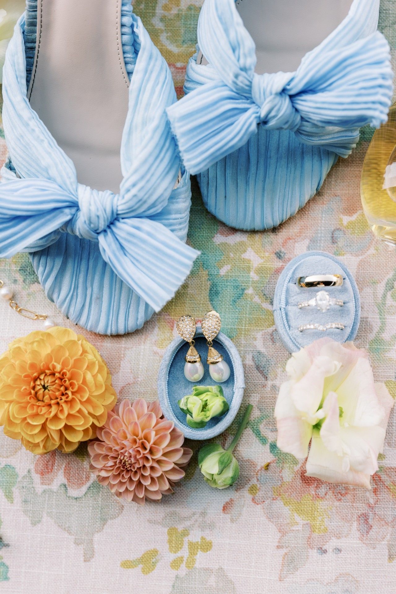 A pair of blue shoes, earrings, rings and flowers on a table by Luxury Wedding Planners in Nashville, TN