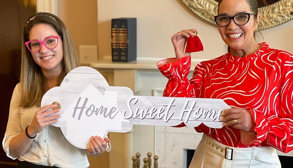 Two women hold a wooden