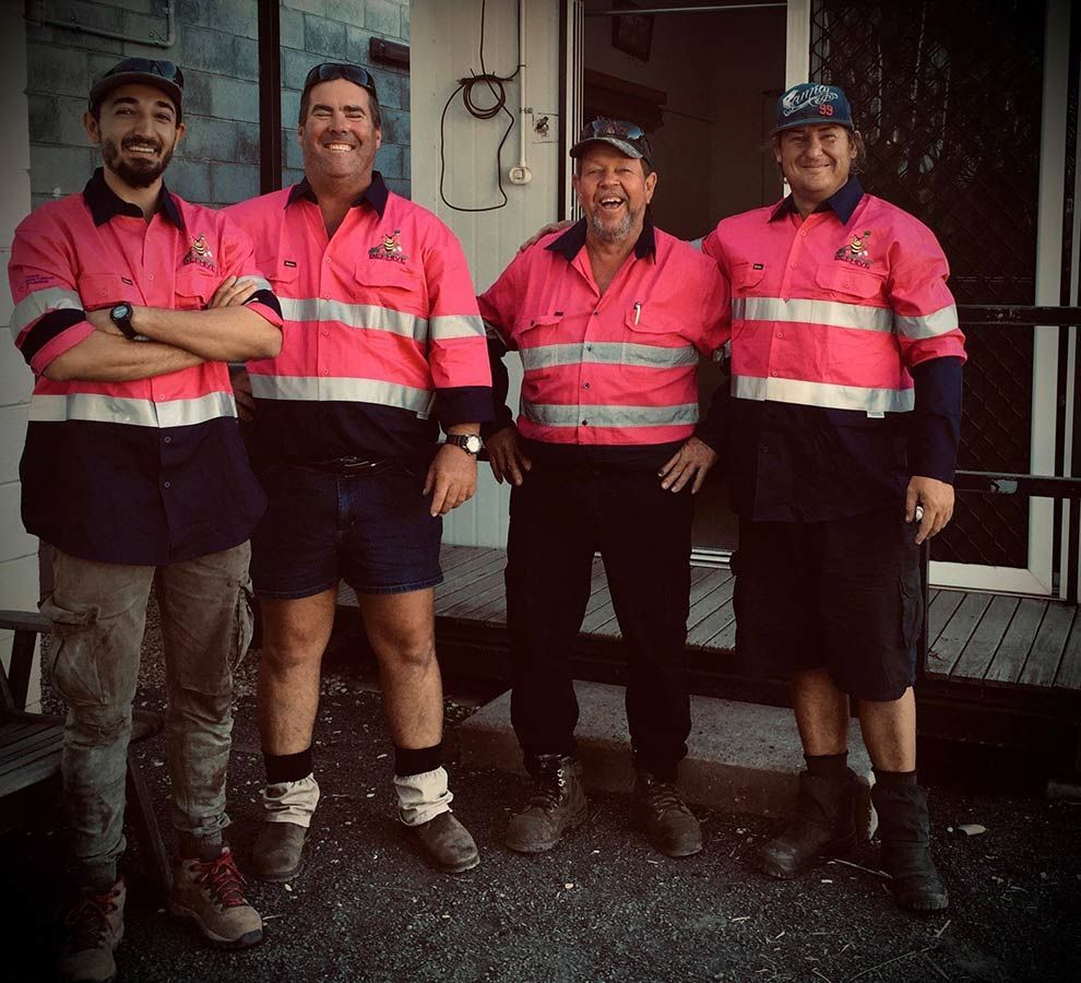 A Group of Men Wearing Pink Safety Shirts Are Posing for a Picture — Beehive Property Maintenance in Emerald, QLD