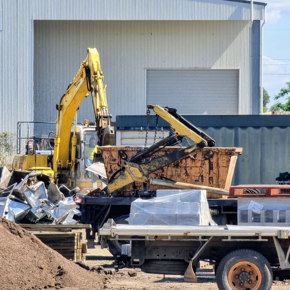 A Bulldozer is Sitting in the Dirt in Front of a House — Beehive Property Maintenance in Capella, QLD