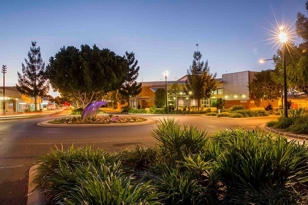 A Roundabout With Trees and Bushes in Front of a Building at Night — Beehive Property Maintenance in Emerald, QLD