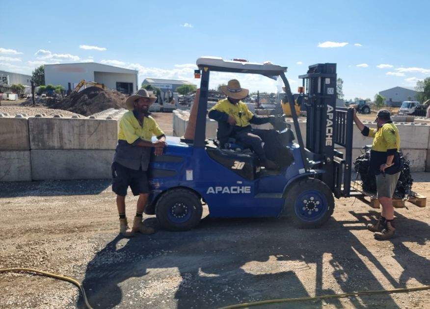A Green Crane is Cutting Down a Tree in Front of a House — Beehive Property Maintenance in Capella, QLD
