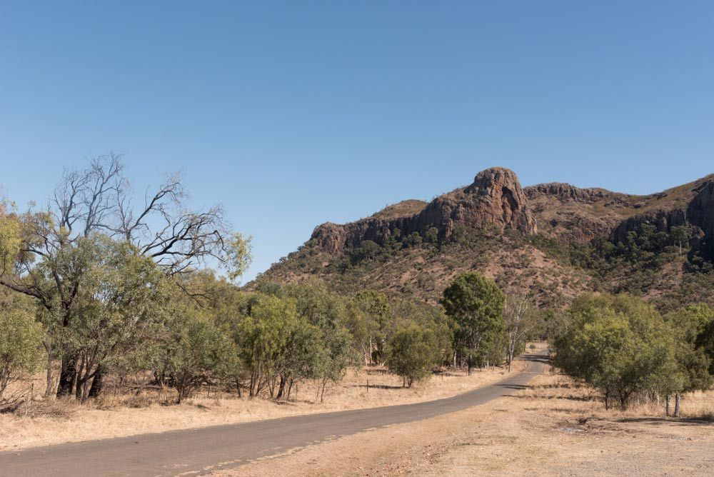 A road in the desert with a mountain in the background — Beehive Property Maintenance in Springsure, QLD