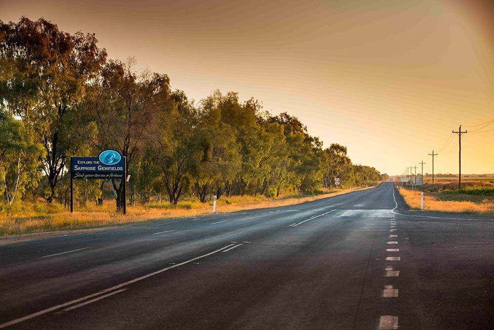 An Empty Highway With Trees on Both Sides and a Sign on the Road — Beehive Property Maintenance in The Gemfields, QLD