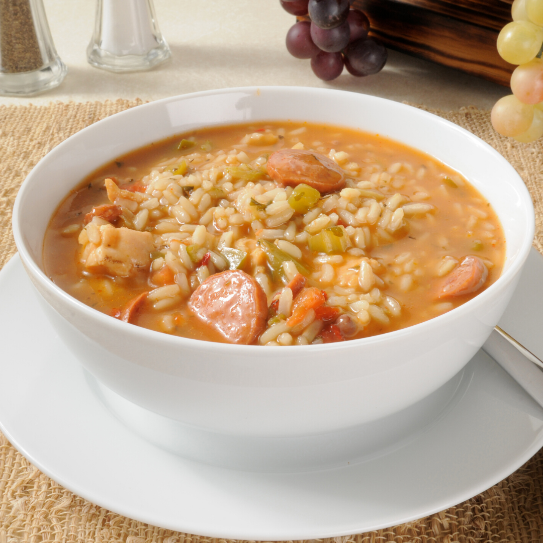 A bowl of soup with rice and sausage on a plate