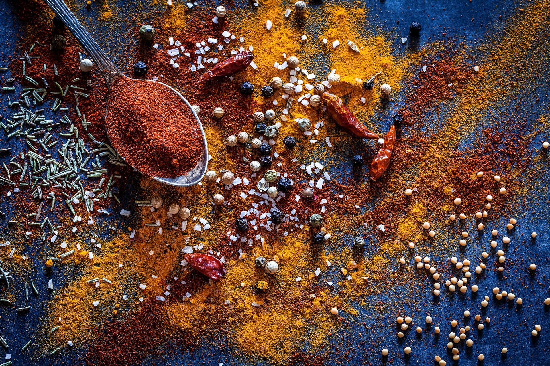 A spoon filled with spices is sitting on top of a pile of spices.