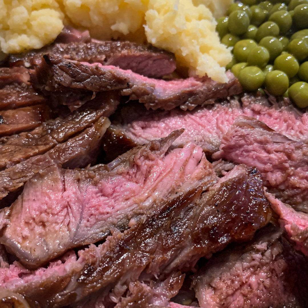 A close up of a plate of meat with mashed potatoes and peas