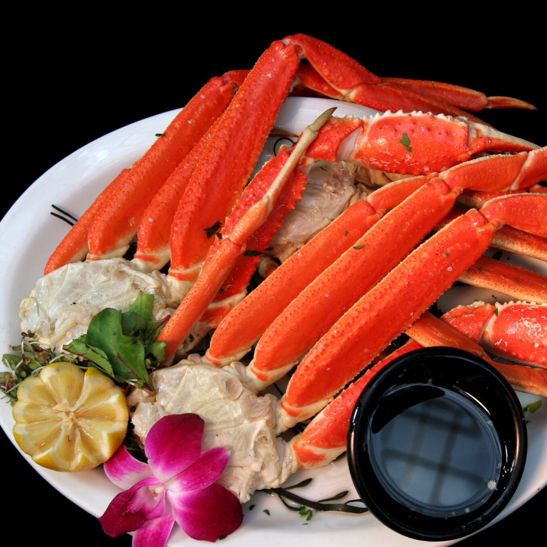 A white plate topped with crab legs and a dipping sauce