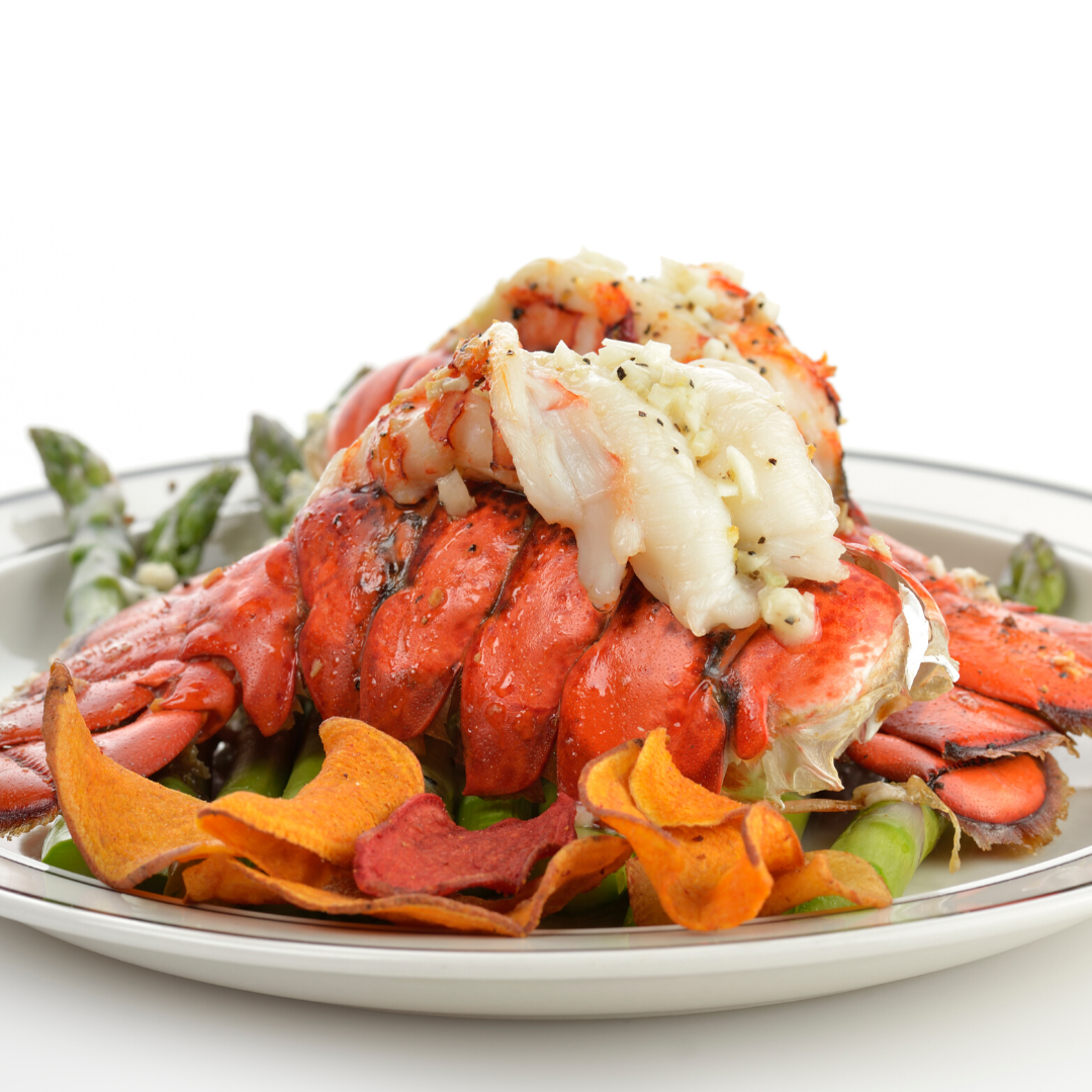 A close up of a plate of food with a lobster on top.