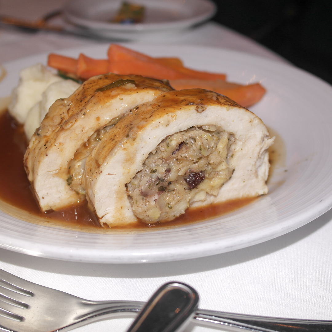 A white plate topped with stuffed chicken and carrots