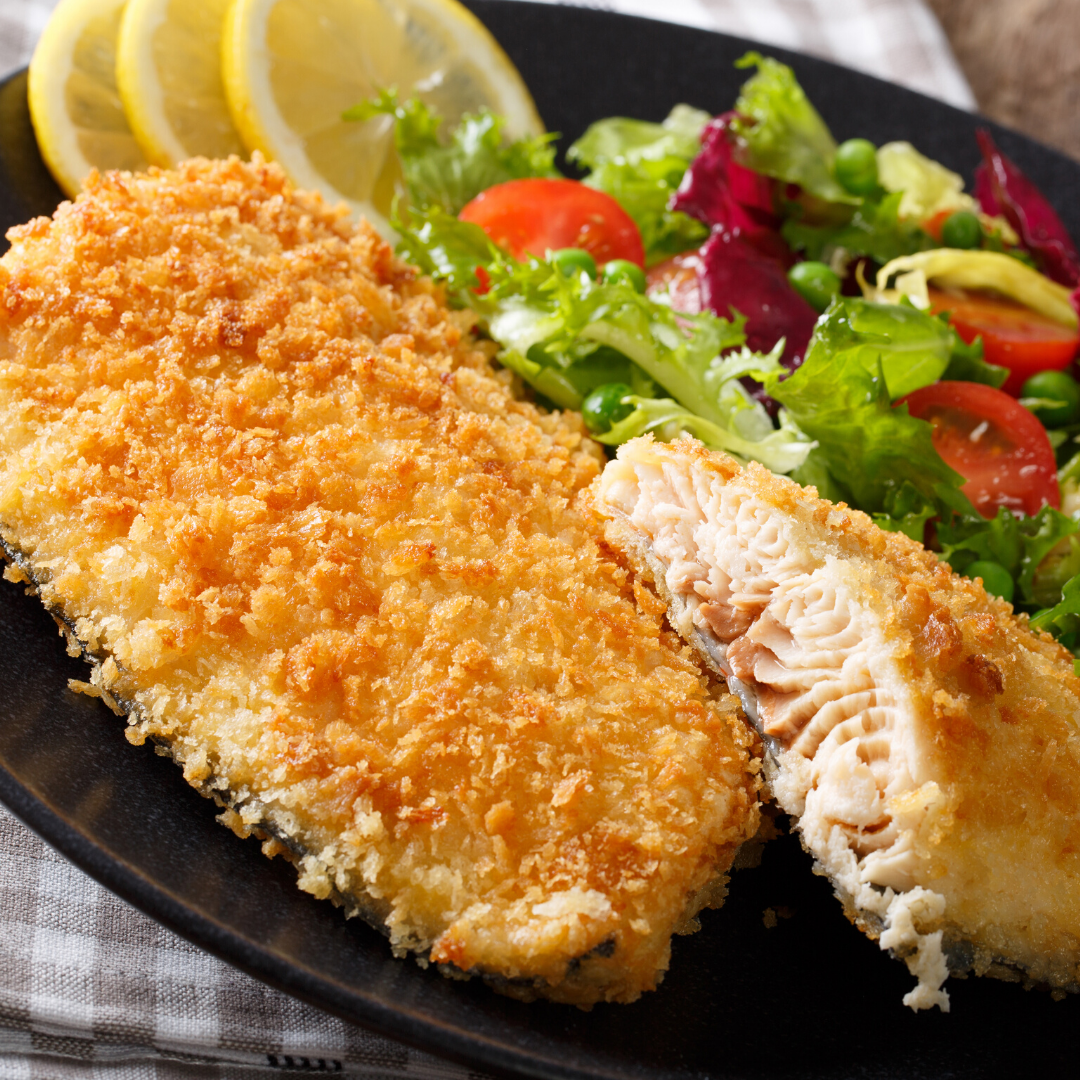 A black plate topped with fried fish and a salad.