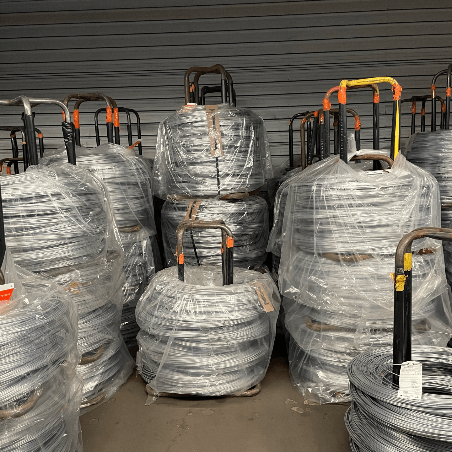 A bunch of rolls of wire are stacked on top of each other in a warehouse.