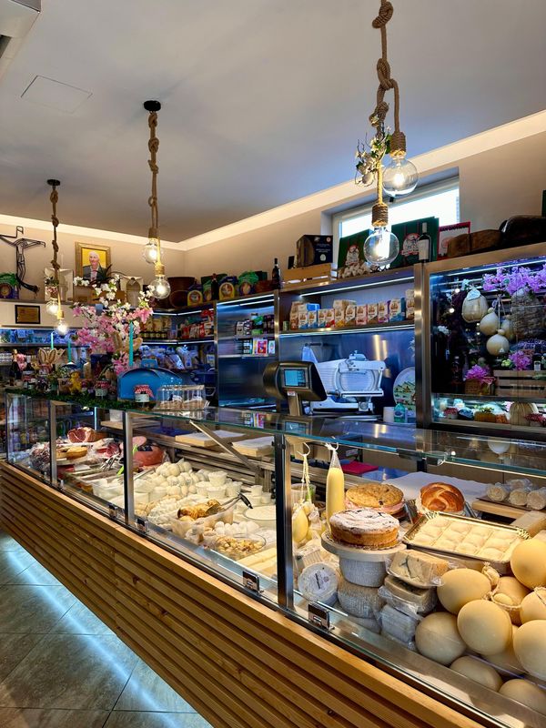 Interno di pasticceria con vetrine espositive di prodotti da forno. Luci soffuse, dettagli in legno e decorazioni.