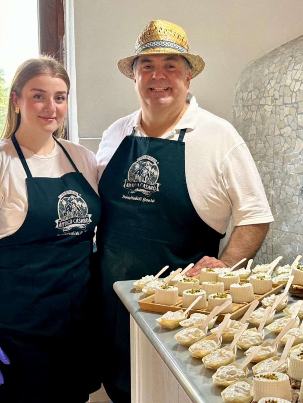 Due persone con grembiuli in piedi vicino a un bancone con antipasti.