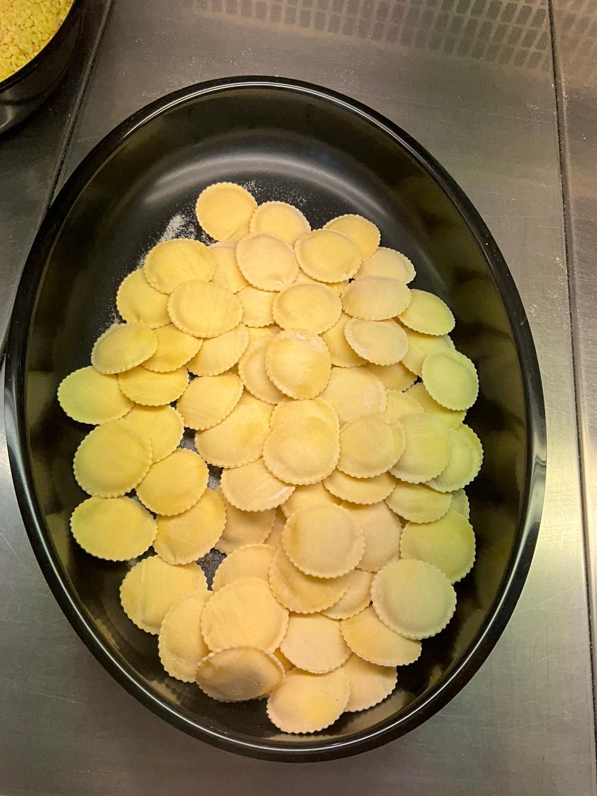 Primo piano di ravioli freschi infarinati; logo Santa Giorgio in un angolo.