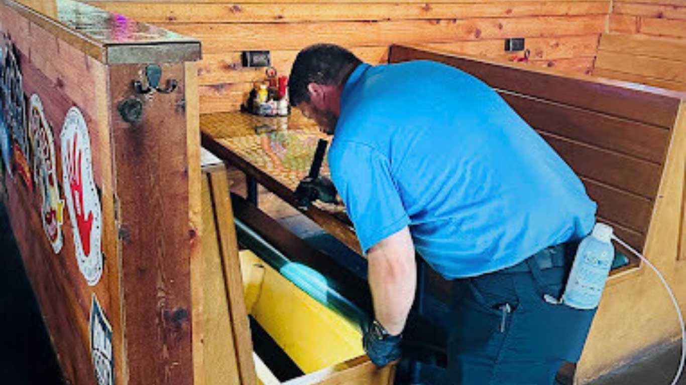 Man in blue shirt, fixing a booth table in a restaurant. Man in blue shirt, fixing a booth table in a restaurant.