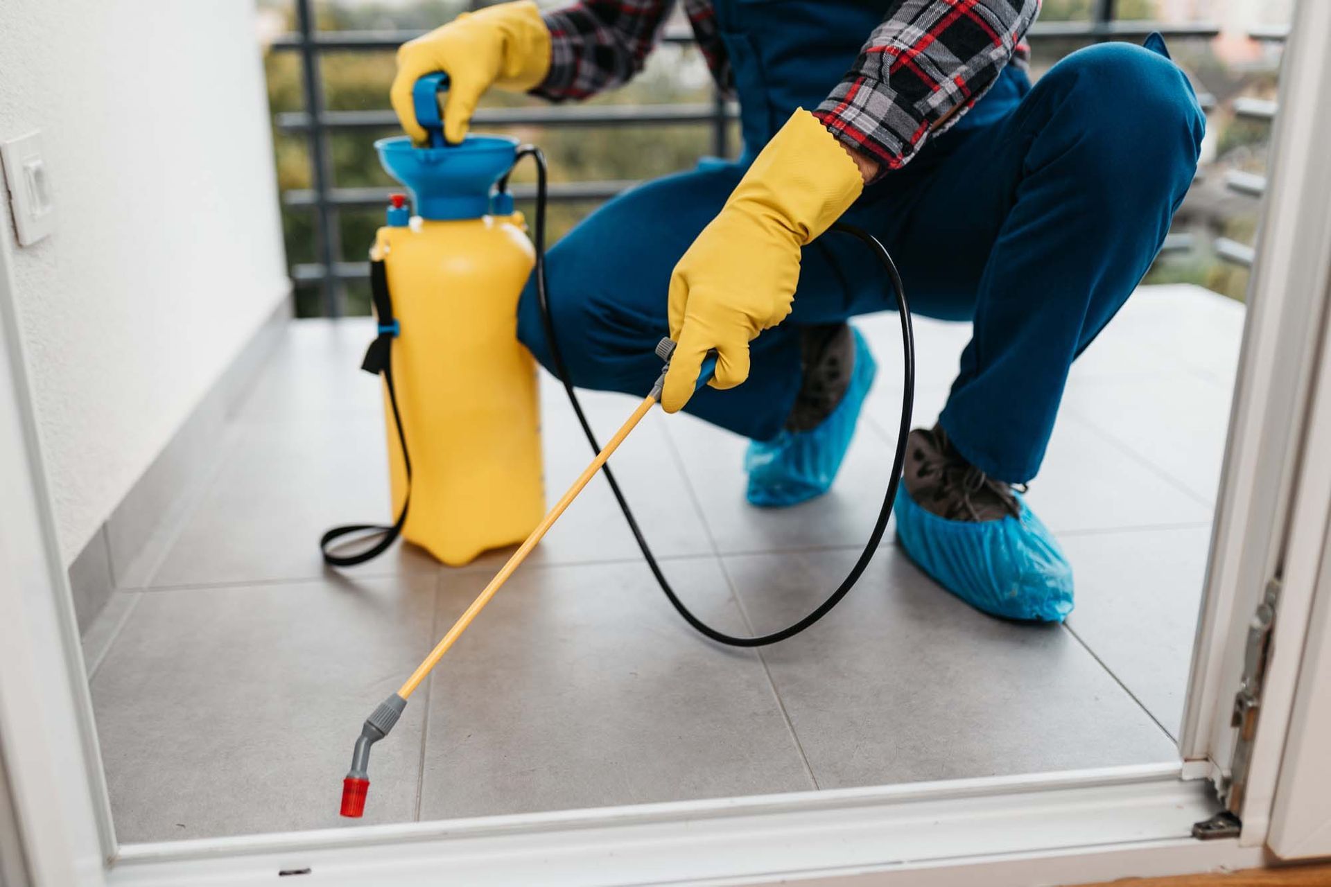 A professional exterminator is spraying pesticide on an apartment balcony. A professional exterminator is spraying pesticide on an apartment balcony.
