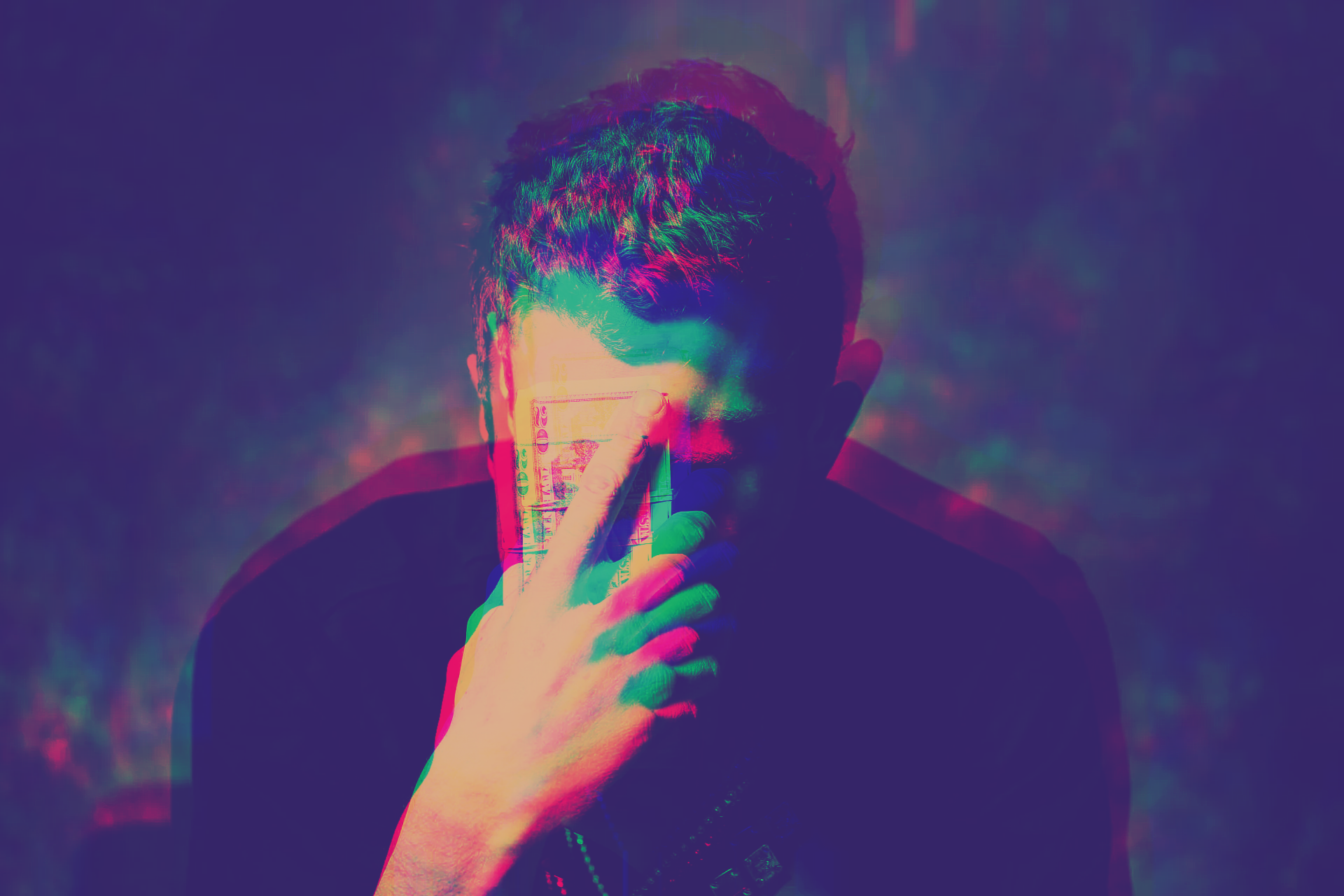 Person with hand over face, with psychedelic color effect.