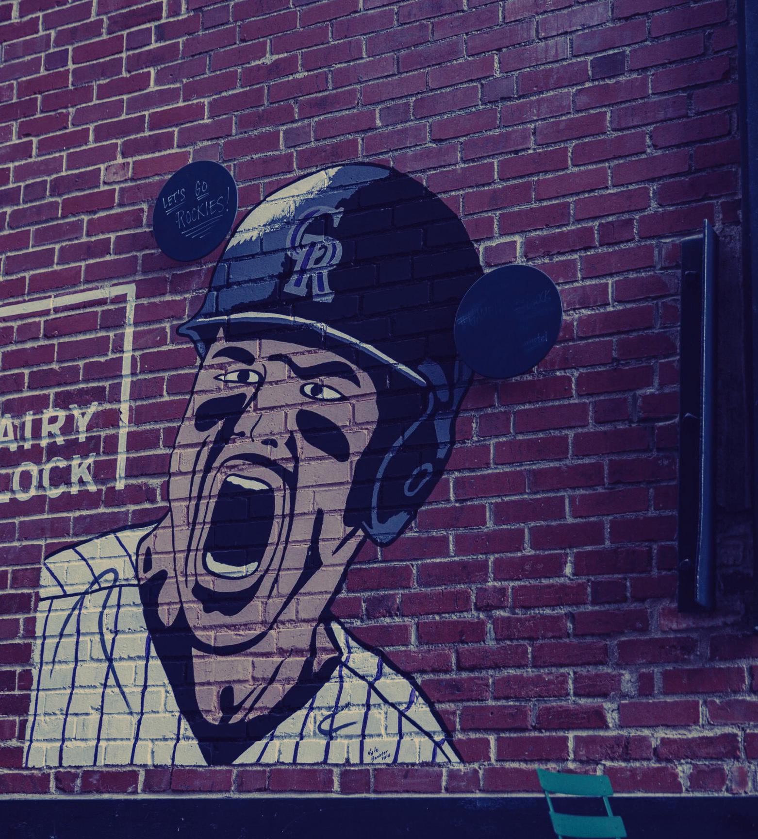 Mural on brick wall: baseball player screaming, wearing helmet with