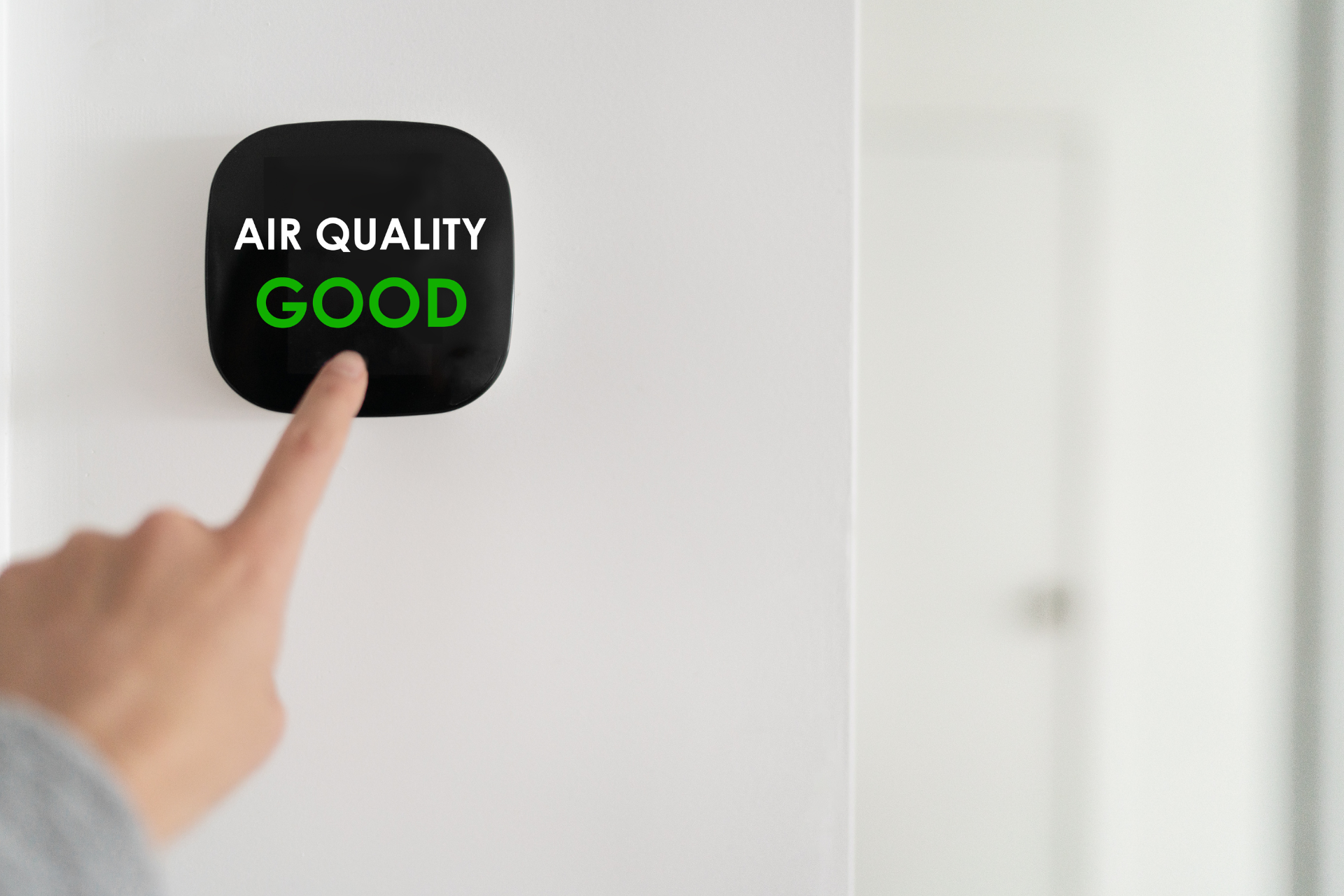 A person is pressing a button on a wall that says `` air quality good ''.