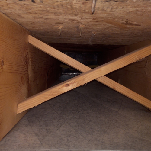 A wooden beam is crossed over another wooden beam