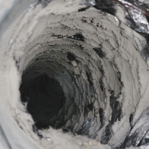 A close up of a dirty duct with a hole in the middle