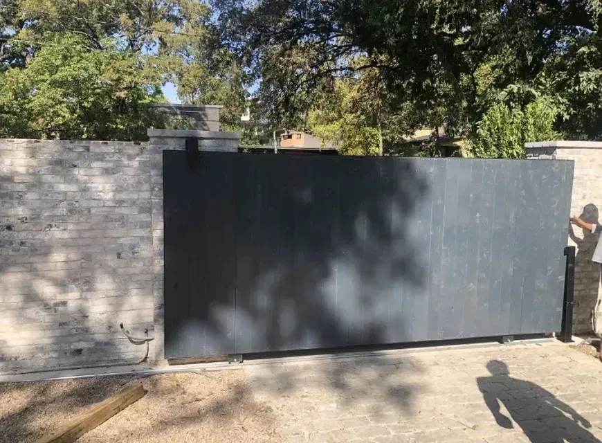 A brick wall with a sliding gate in front of it.