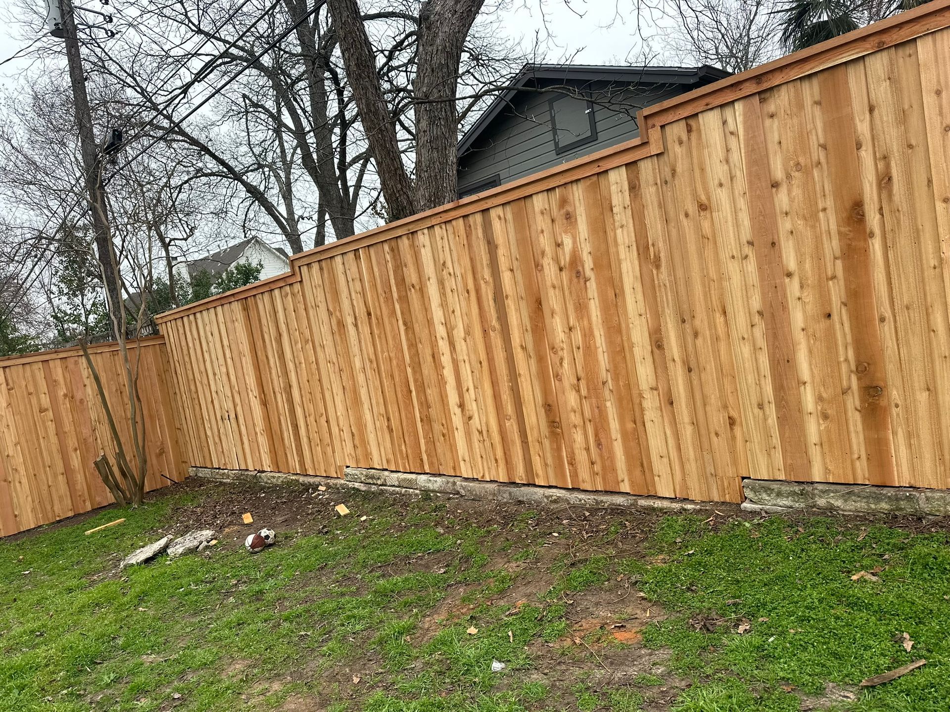 A wooden fence is in the backyard of a house.