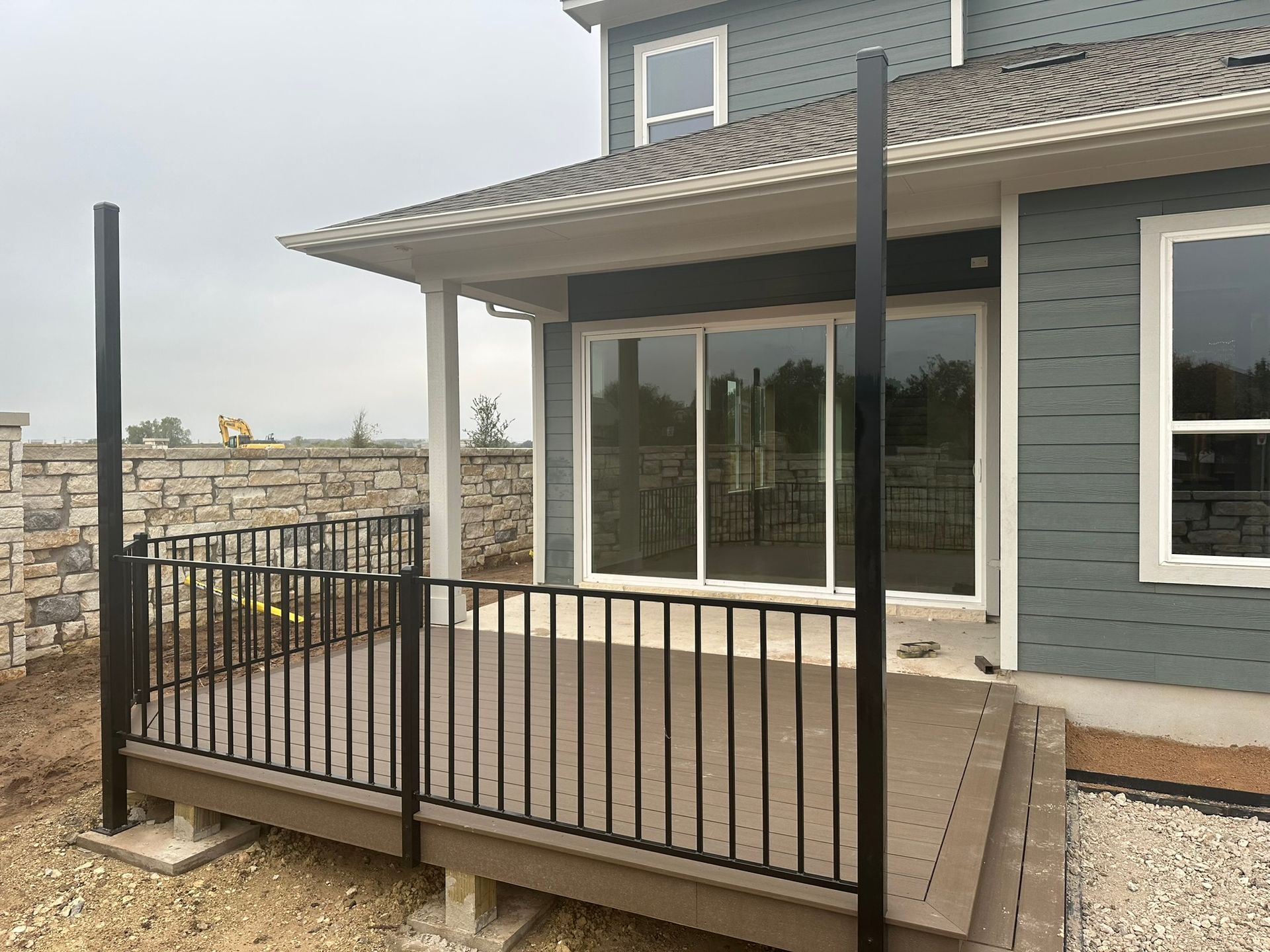 There is a deck with a railing in front of a house.