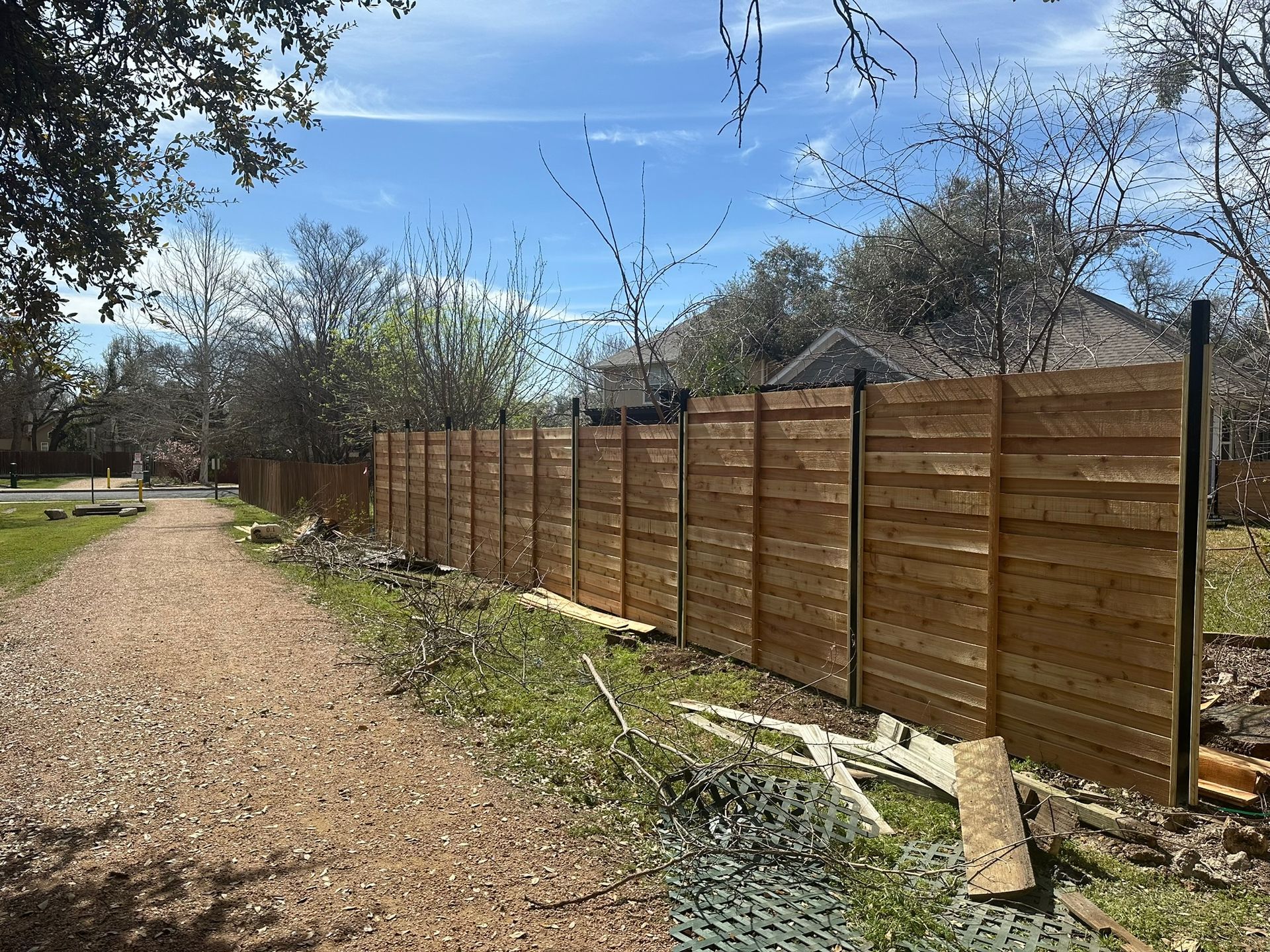 A wooden fence is being built on the side of a dirt road.