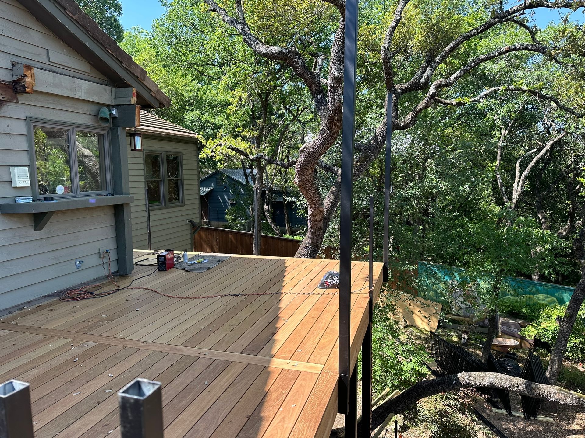 A wooden deck is being built in front of a house surrounded by trees.