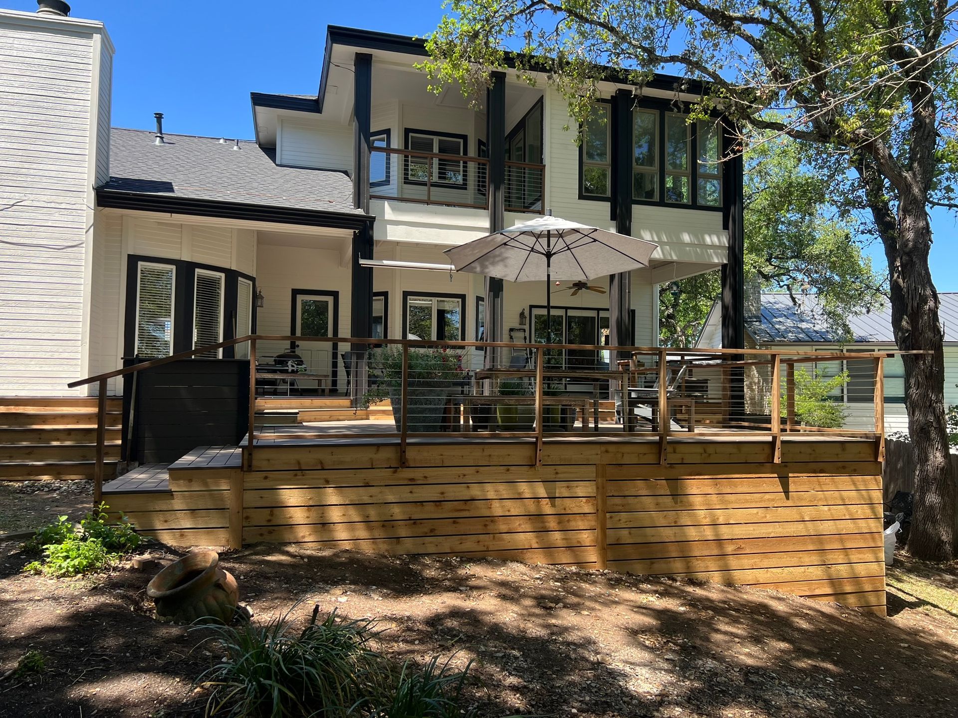 The back of a house with a wooden deck and umbrella.