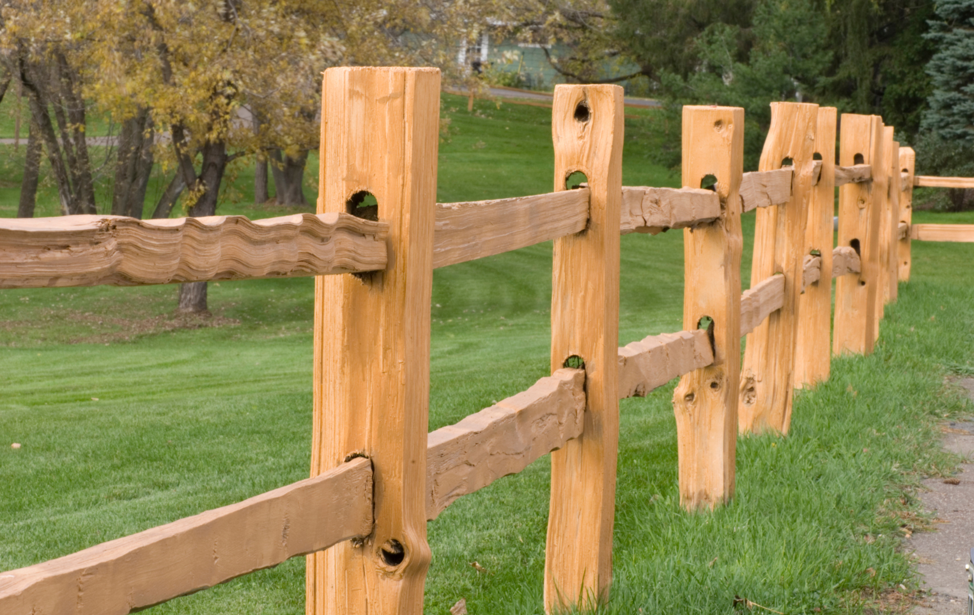 A wooden fence surrounds a lush green field.