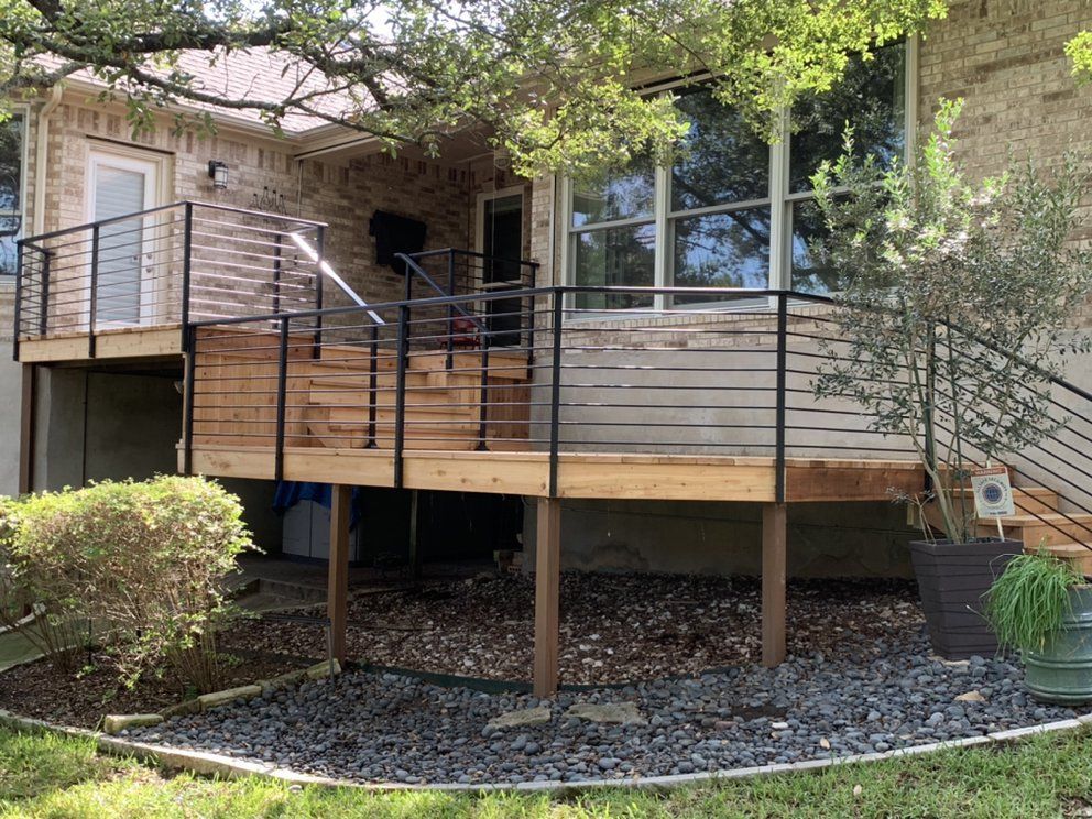 A wooden deck with a metal railing is in front of a house.