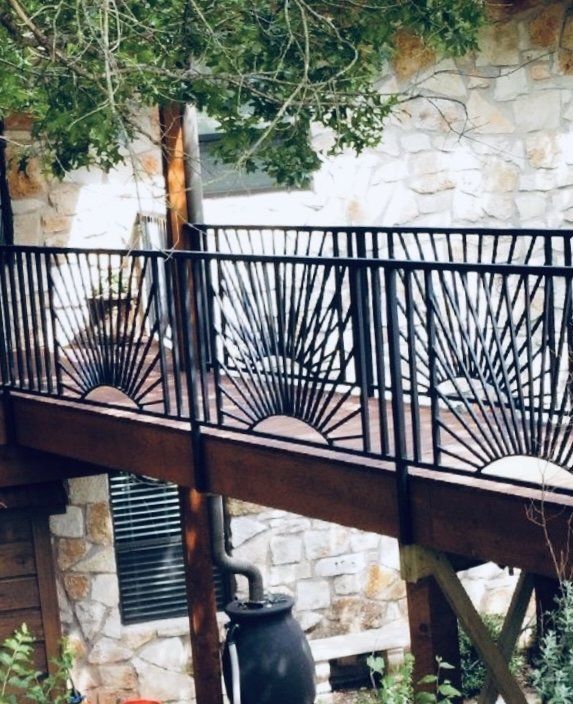 A wooden deck with a wrought iron railing leading to a stone building