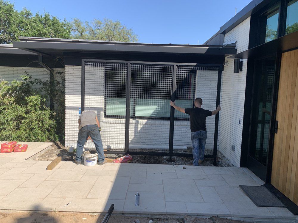Two men are working on a fence in front of a house.