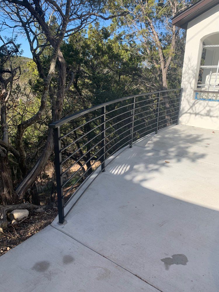 A concrete deck with a metal railing and trees in the background.