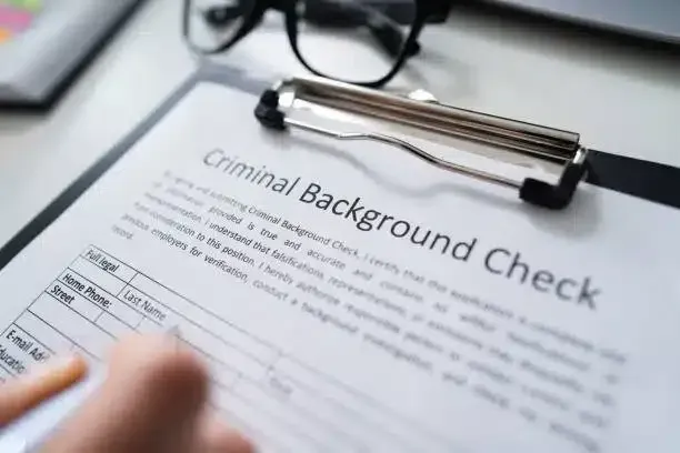 A person is filling out a criminal background check on a clipboard.