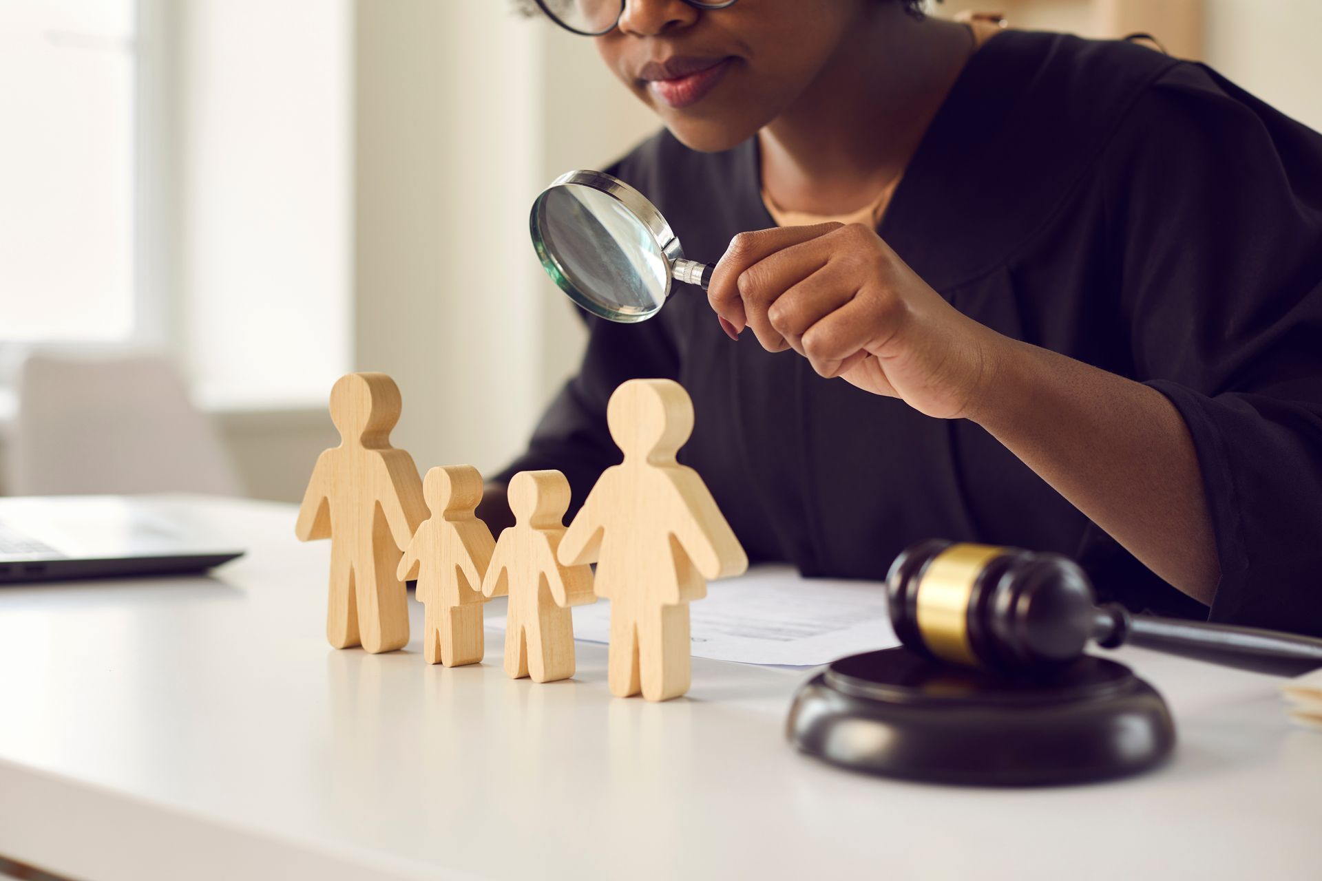A woman is looking through a magnifying glass at a wooden family.