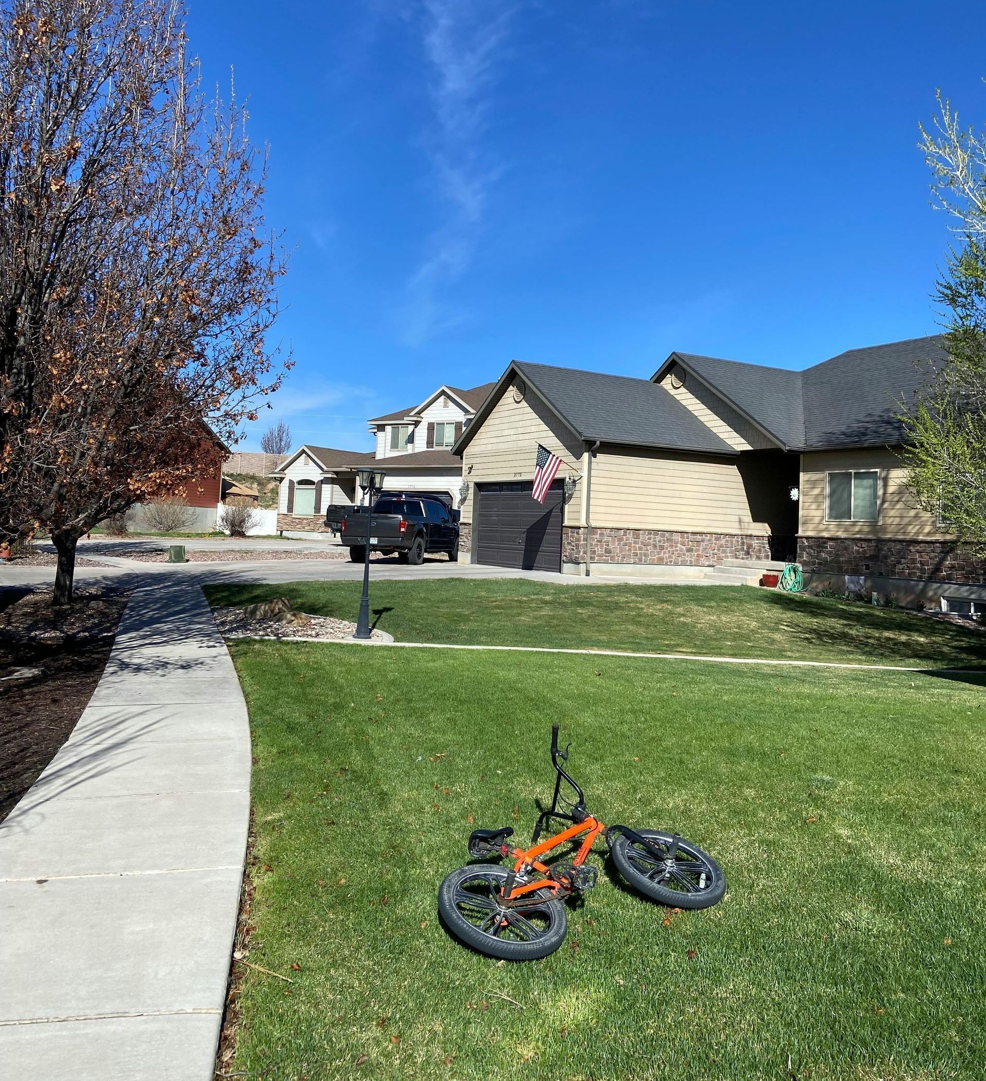 A bicycle is parked in the grass in front of a house.