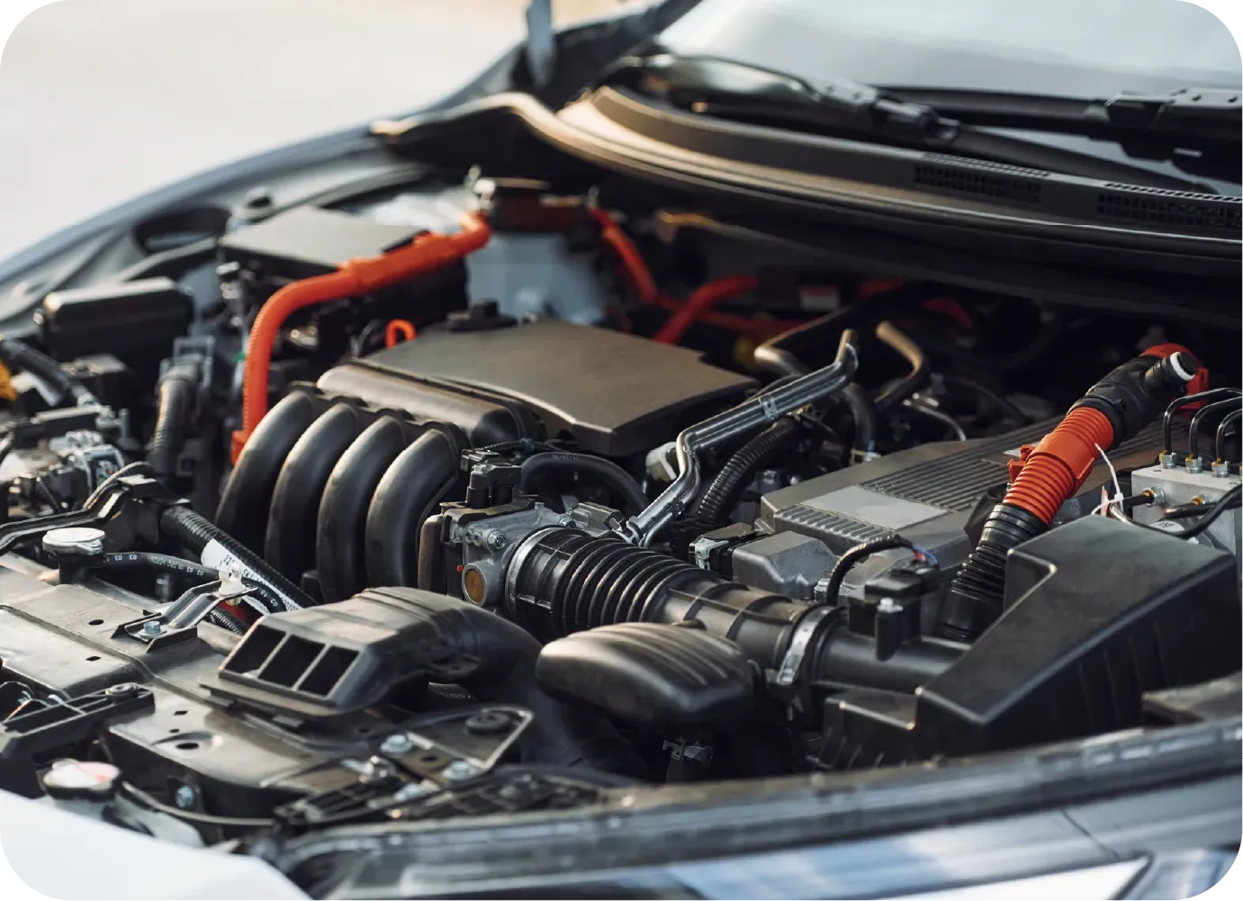 A mechanic uses a tool to work on the engine of a vehicle in an auto repair shop.