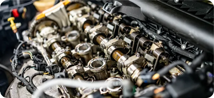 A close-up view of an open internal combustion engine showing exposed camshafts, valves, and mechanical components.