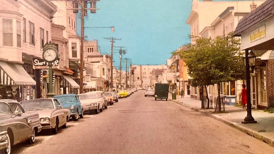 A row of cars are parked on the side of a city street.