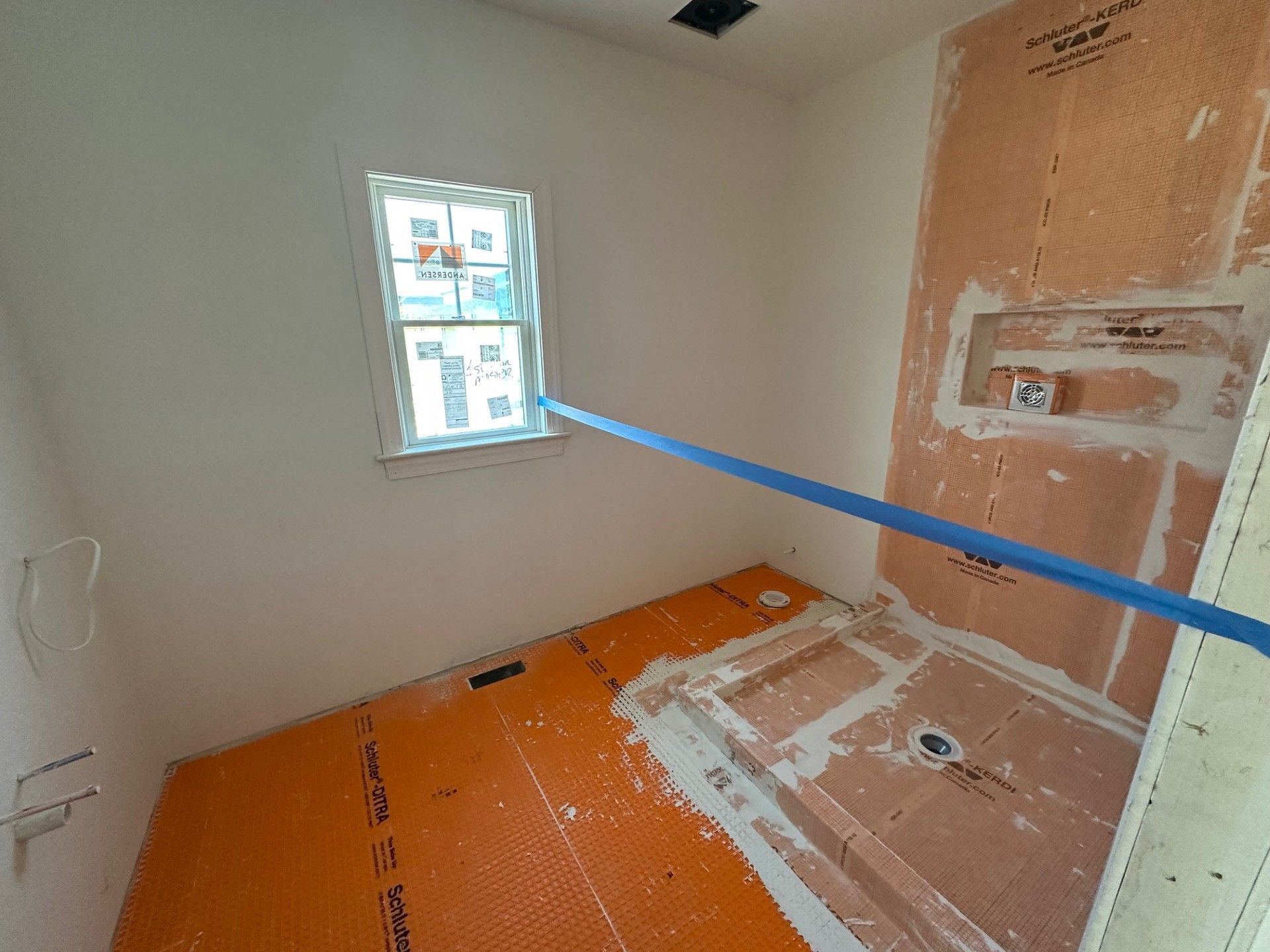 A bathroom under construction with a window and a blue tape measure.
