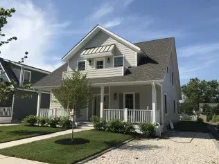 A white house with a gray roof and a large porch.