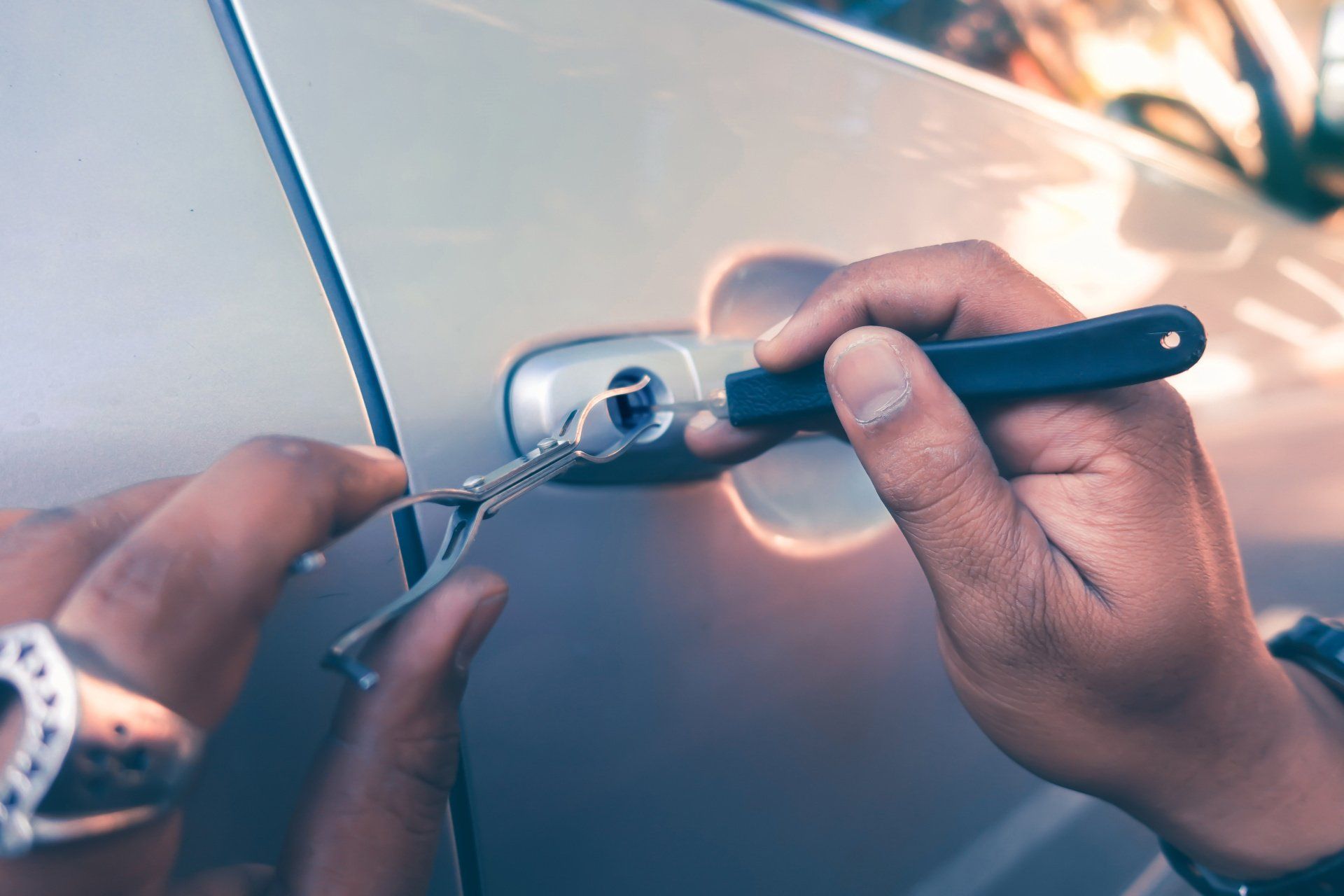 Locksmith attempting to unlock a car door using a lockpicker tool.