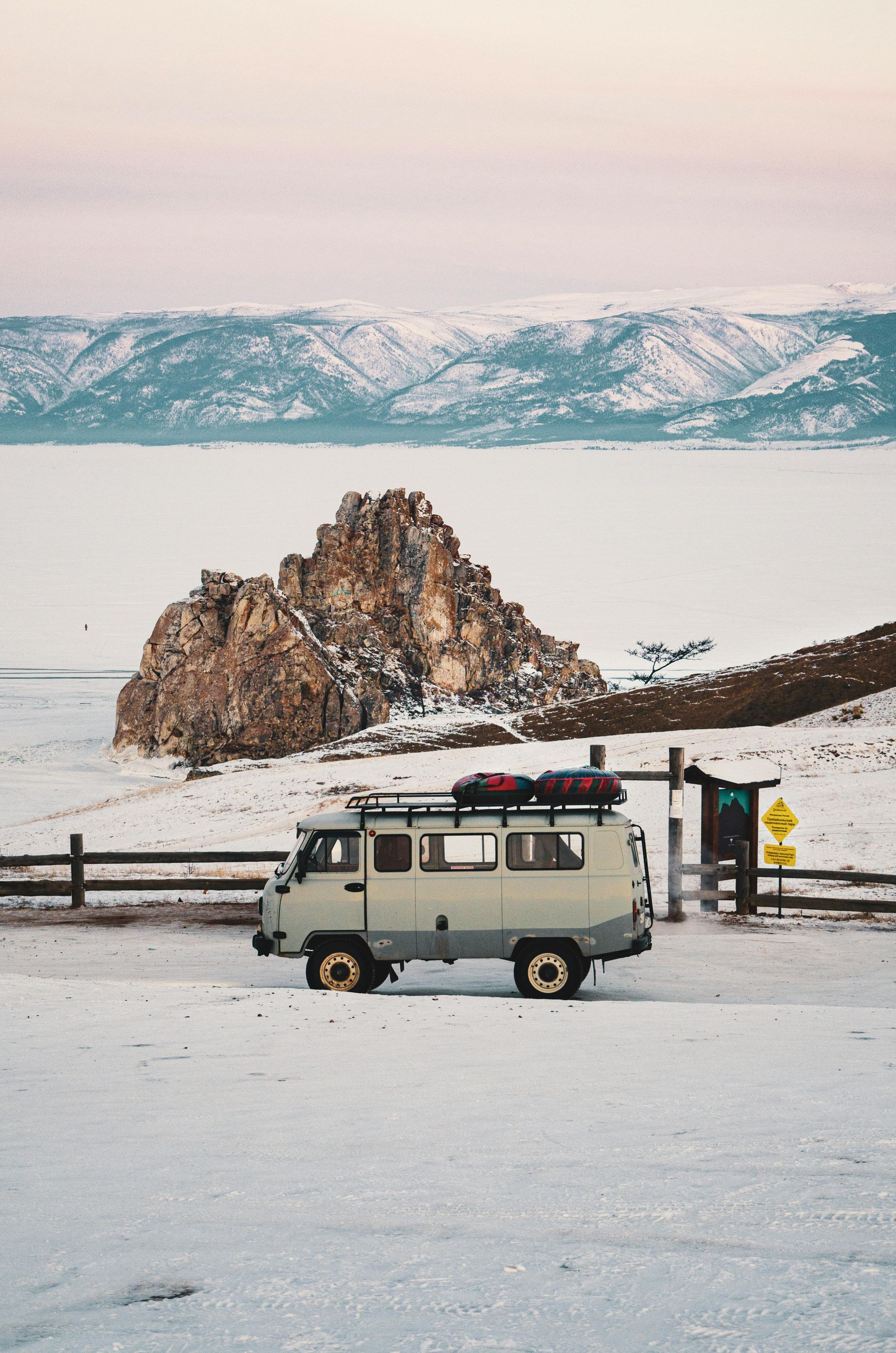 A van is parked in the snow near a lake.