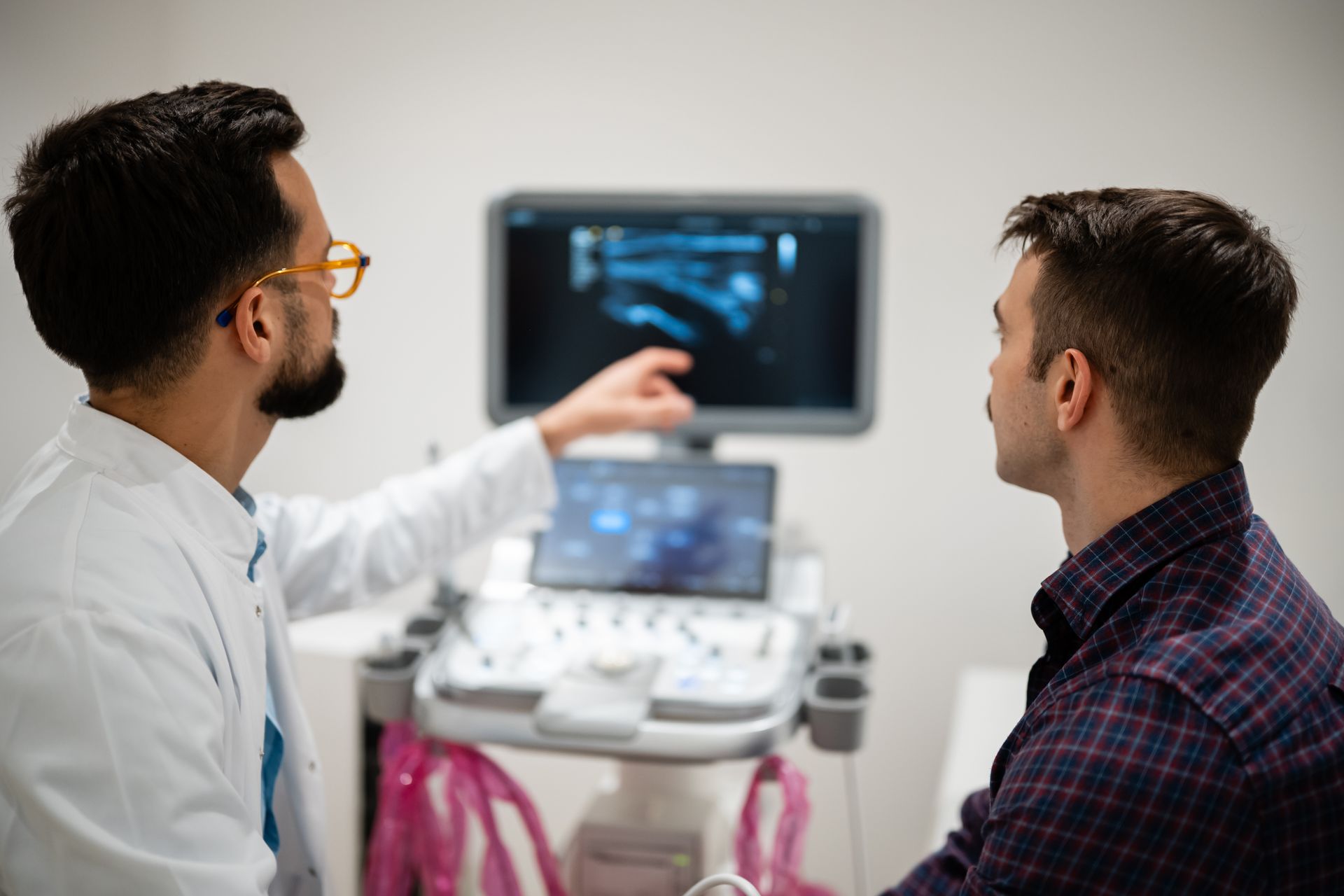 Doctor reviewing ultrasound results with a male patient in a consultation room. Doctor reviewing ultrasound results with a male patient in a consultation room.