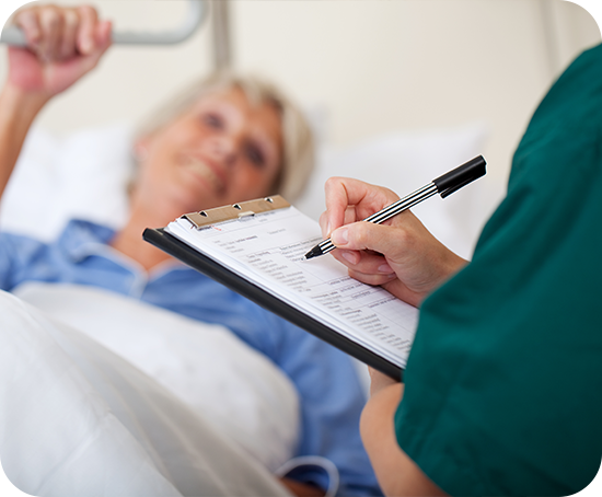 A nurse is writing on a clipboard next to a patient in a hospital bed